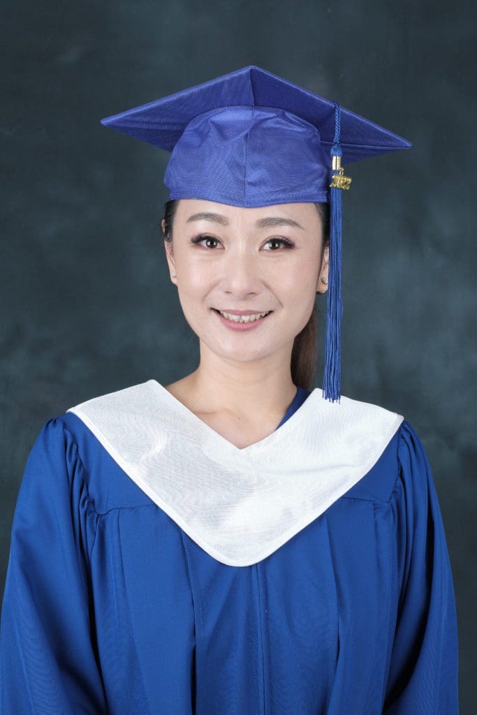 CArol wearing a royal blue graduation cap and gown with a white v-stole,