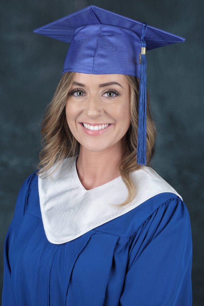 Hannah wearing a royal blue graduation cap and gown.