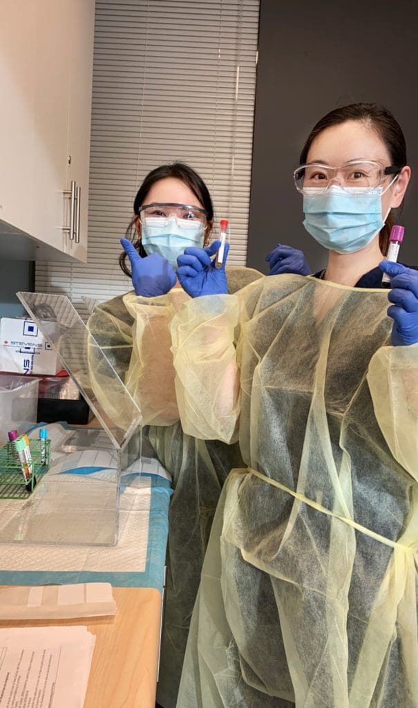 Carol and a classmate work in the lab wearing pull PPE