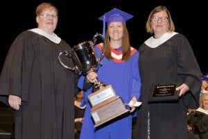 Debra Andrew holds her Student of the Year trophy, given by the hands of her Psych Nursing instructors.