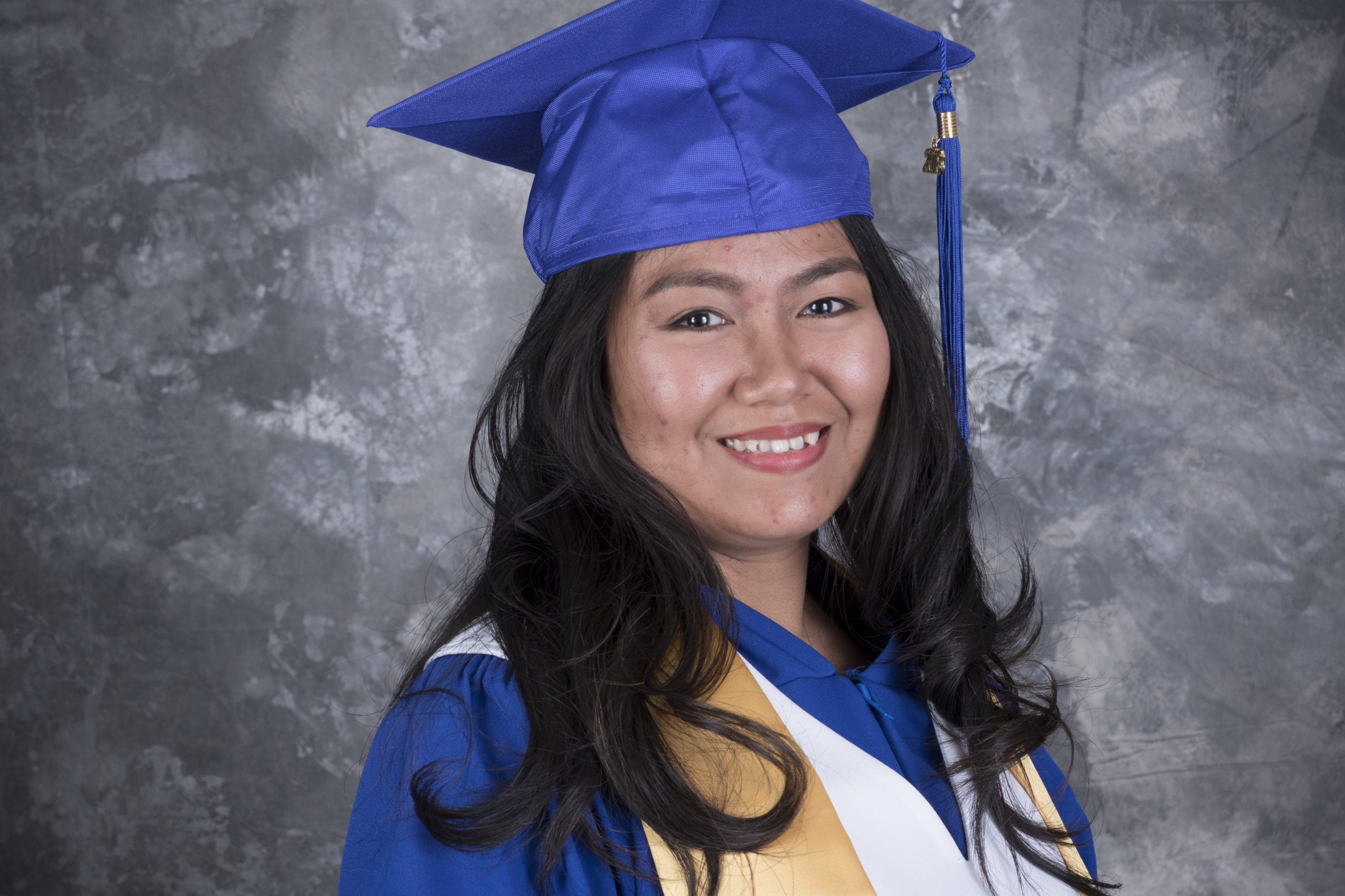 Faith Samson happy in a grad gown after completing her course as an Education Assistant.