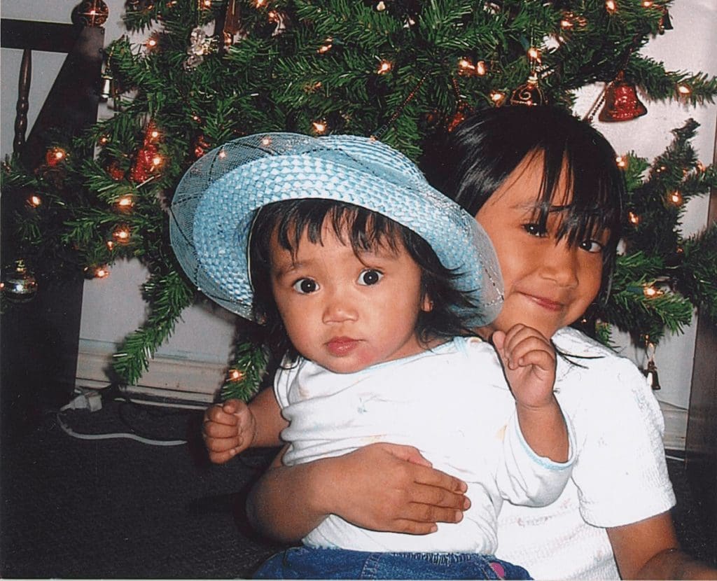 Justine as a child with her sister celebrating Christmas in the Philippines.