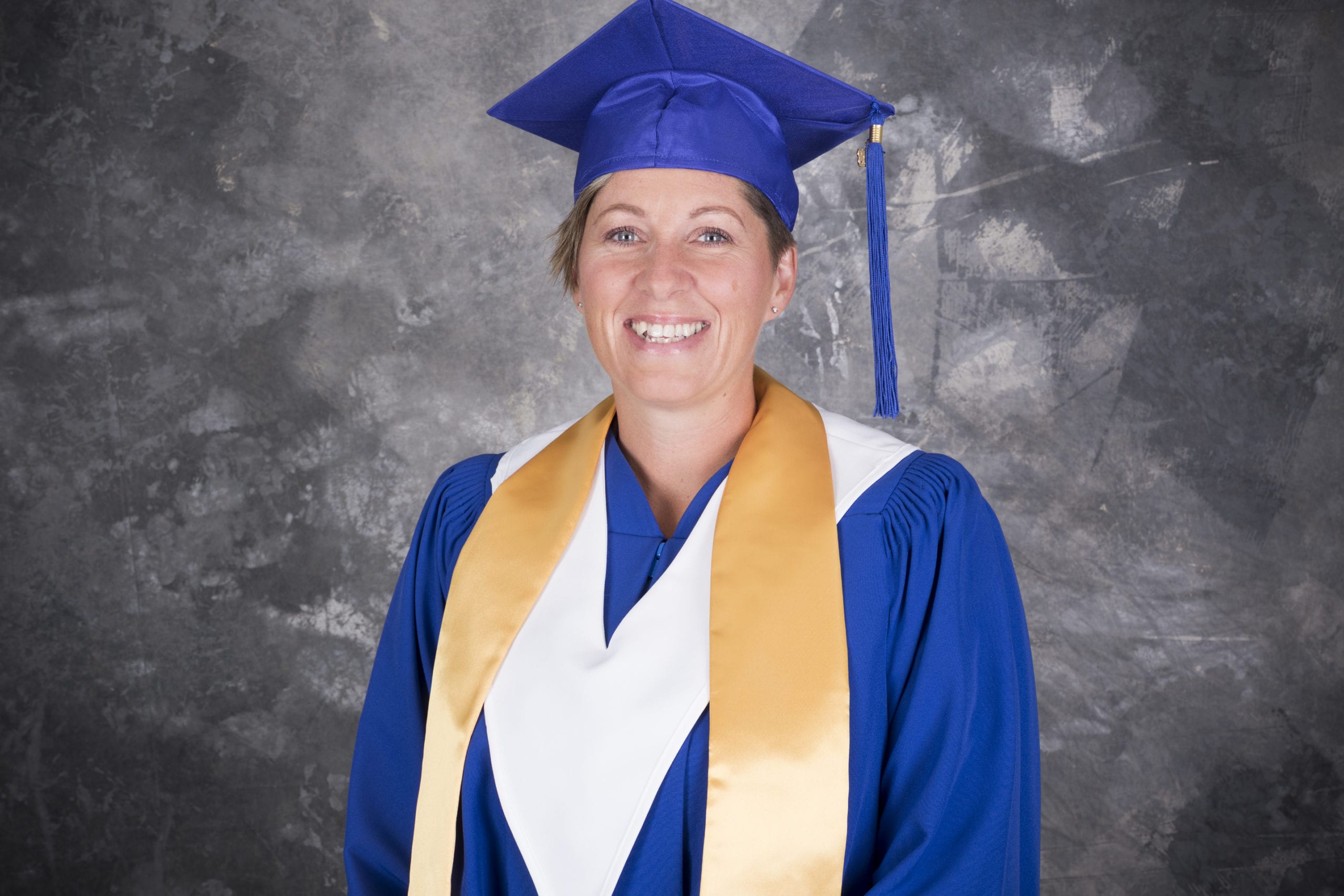 Lindsay in Graduation gown, smiles proudly after working hard and finishing the Nursing Unit Clerk course.