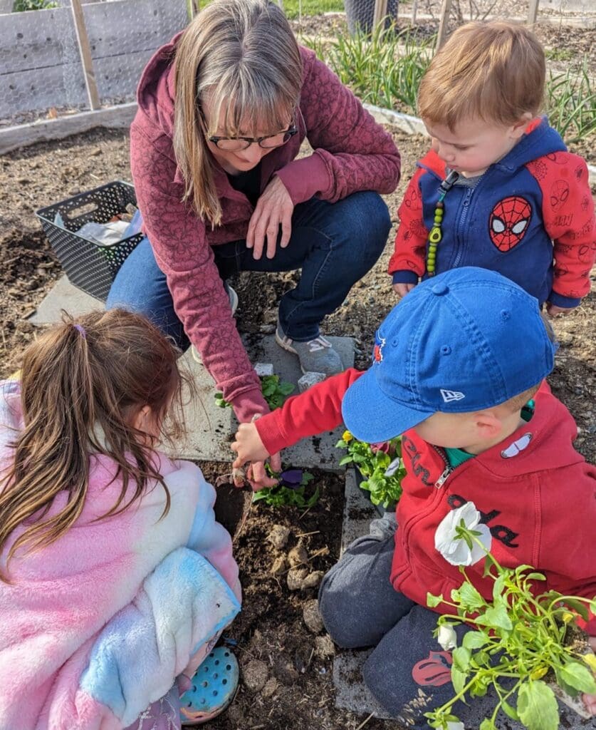 Carol Mohanraj gardening with her grandchildren on a sunny day.